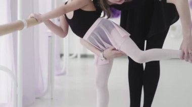 Bale öğretmeni profesyonel balerin, bale barında kızlara bacak hareketleri ve kıvrımlar öğretiyor.