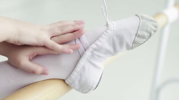 Крупный план маленьких девочек, использующих балетную планку при выполнении упражнений на растяжку ног в танцевальной студии — стоковое видео