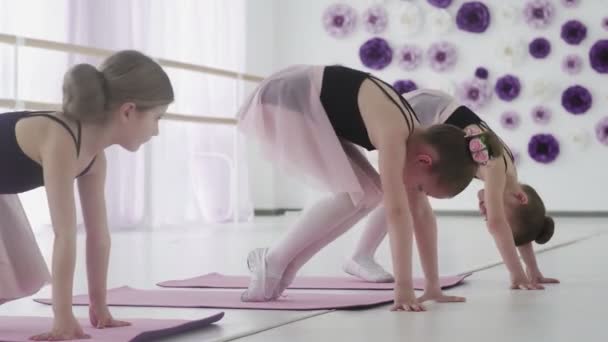 Unga balettdansare gör övningar på golvet — Stockvideo