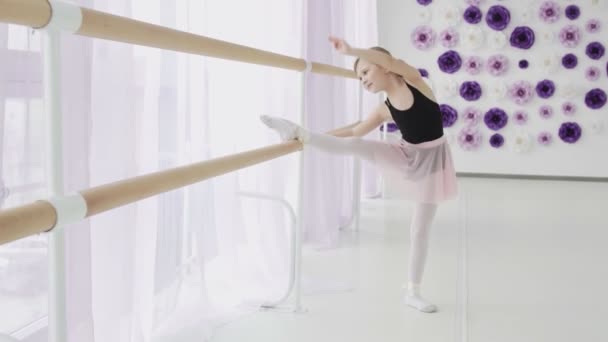 Kleine Mädchen mit Ballettbarre bei Beinstreckübungen im Tanzstudio — Stockvideo