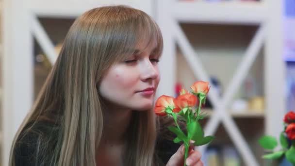 Una joven oliendo una flor en una tienda — Vídeos de Stock