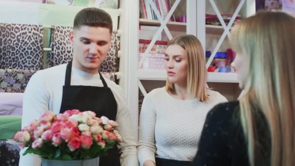 Ung glad man och vackra kvinna blomsterhandlare pratar med kunden och ger råd — Stockvideo