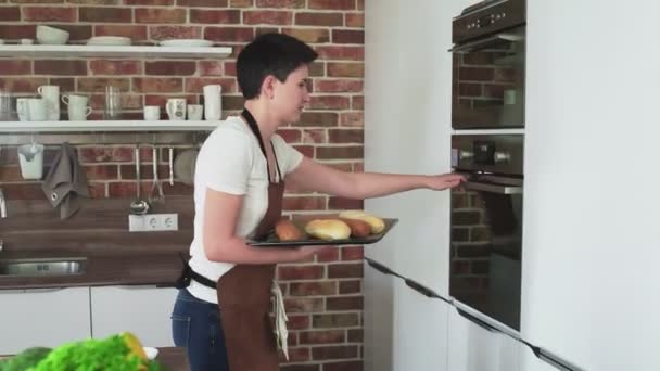 O femeie care pune pâine cu gheaţă la cuptor . — Videoclip de stoc