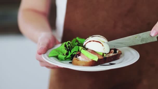 Kvinna som håller i en bruschetta med avokado, pocherat ägg, lax och keso — Stockvideo