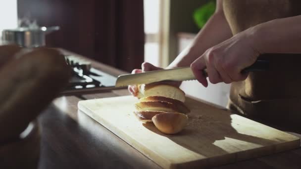 Kvinnliga händer skära bröd limpa med kniv på hemkök — Stockvideo