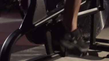 Spor giyim bölümünde yakın plan erkek ayağı spor salonunda spor bisikletinde pedal çeviriyor.