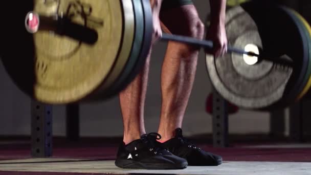 Vista lateral del hombre realizando ejercicio de elevación mortal con barra de peso. Confiado joven haciendo levantamiento de pesas barra de entrenamiento en el gimnasio crossfit . — Vídeo de stock