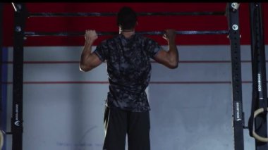 Sporcu Genç Adam Crossfit spor salonunda barfiks çekiyor..