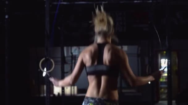 Athletic Beautiful Woman bär sportkläder övningar med hoppa rep i Hardcore Gym. — Stockvideo