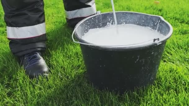 Bereiten Sie sich auf die Markierung des Fußballplatzes vor. Das Mischen weißer Farbe mit dem Bohrer im Eimer — Stockvideo