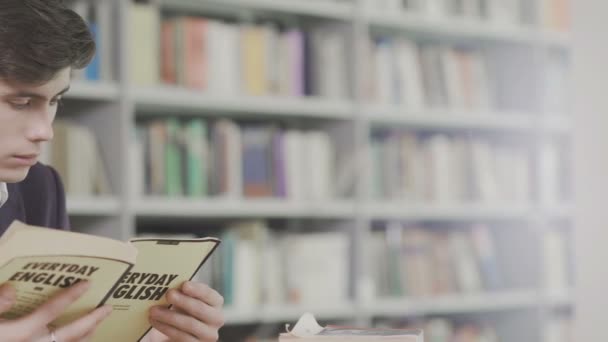 Mladý student pilně studuje v knihovně. Muž univerzitní student dělá výzkum v knihovně s knihami — Stock video