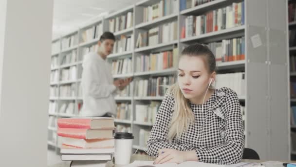 Twee Kaukasische universiteitsstudenten die zich voorbereiden op een examen in de bibliotheek — Stockvideo