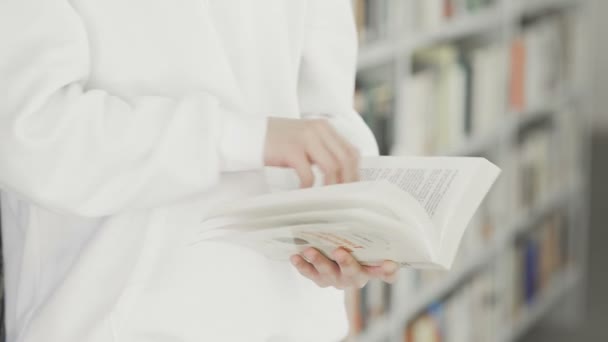 Estudiante está leyendo libro en la biblioteca — Vídeo de stock