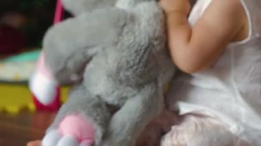 Güzel küçük bir kız yumuşak bir oyuncakla oynuyor.