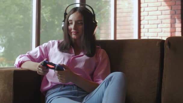 若いです女性とヘッドフォン再生ビデオゲームジョイスティックを使用して — ストック動画