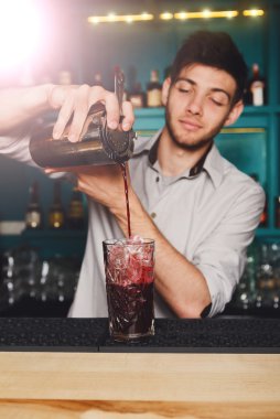 Genç yakışıklı barmen kokteyl içki cam içine dökme