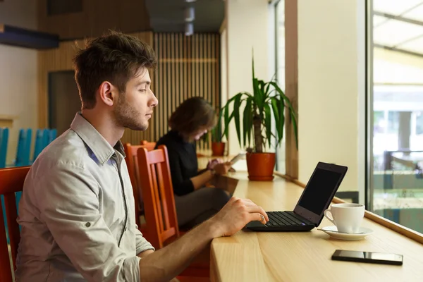 Joven con portátil en el café de la ciudad, freelancer — Foto de Stock