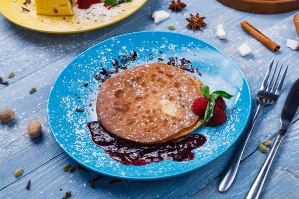 Restaurant dessert. Pancakes with raspberry sauce on blue wood — Stock Photo, Image