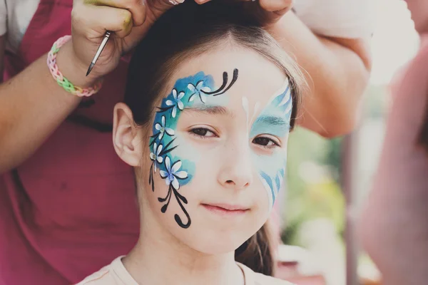 Female child face painting, making butterfly process