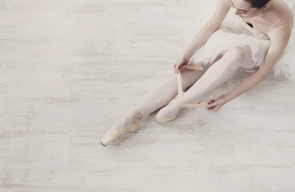 Ballerina puts on pointe ballet shoes, graceful legs — Stock Photo, Image