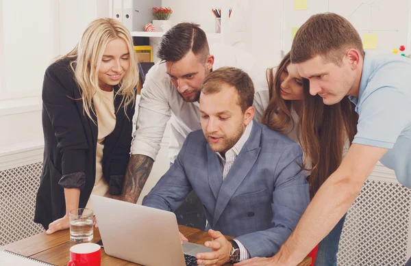 Gente de negocios feliz se unen cerca de la computadora portátil en la oficina — Foto de Stock