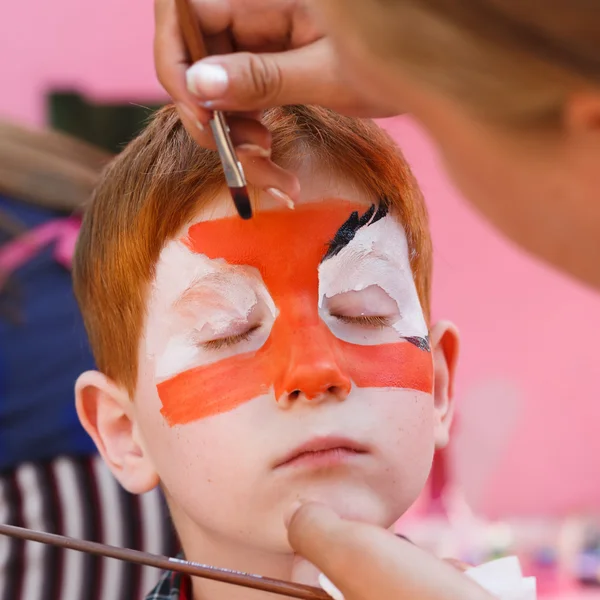 Criança menino rosto pintura, fazendo tigre olhos processo — Fotografia de Stock