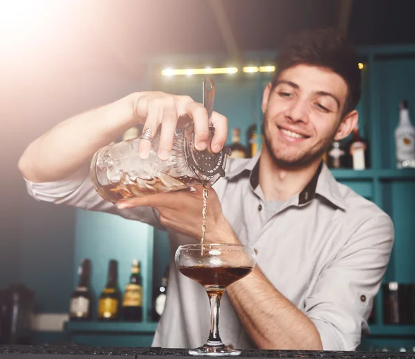 Young Barman mixing cosmopolitan cocktail