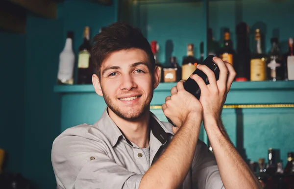 Jovem barman bonito no bar tremendo e misturando coquetel de álcool — Fotografia de Stock