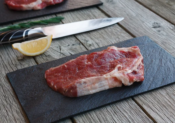 Steak de boeuf cru sur fond de table en bois foncé — Photo