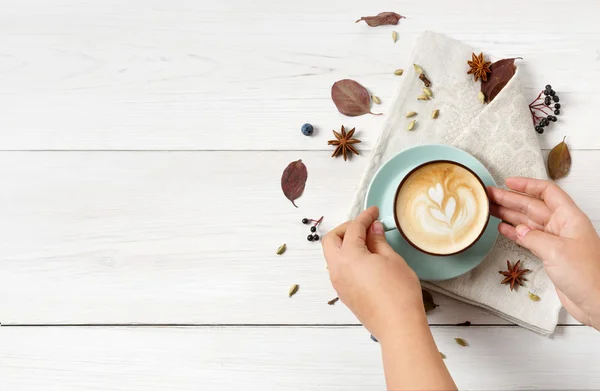 Woman has autumn cappuccino coffee, top view on white wood — Stock Photo, Image