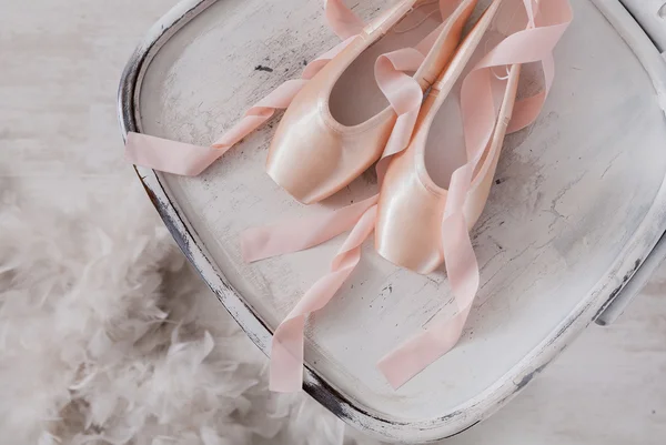 Balé rosa aponte sapatos e penas no fundo de madeira branca — Fotografia de Stock