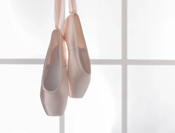 Růžová baletní pointe boty visí na okně — Stock fotografie