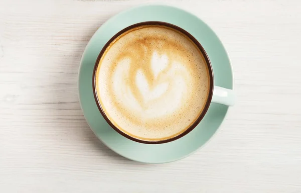 Espuma de capuchino, taza de café vista superior sobre fondo de madera blanca — Foto de Stock