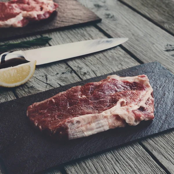 Raw beef steak on dark wooden table background — Stock Photo, Image