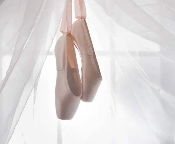 Розовая балетная пуанта обувь висит на окне — стоковое фото