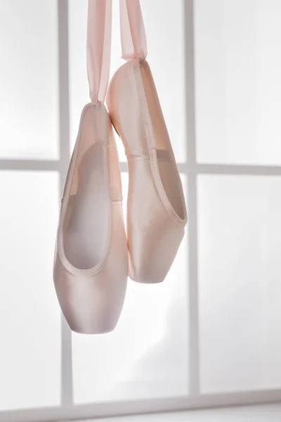 Růžová baletní pointe boty visí na okně — Stock fotografie