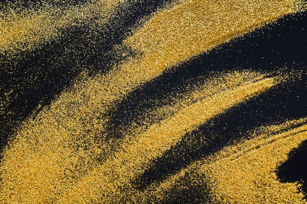Sandmalerei. Goldglitzer auf schwarzem, abstraktem Hintergrund. — Stockfoto