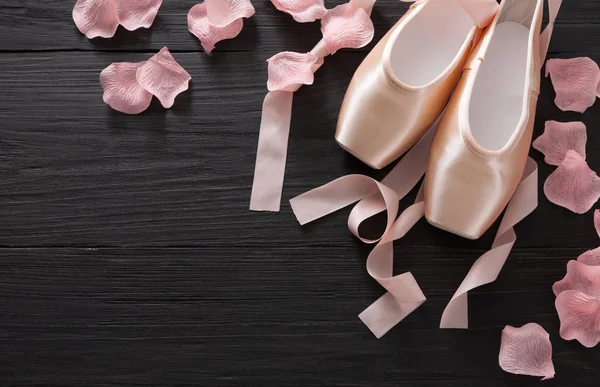 Розовые балетные пуанты туфли на фоне черного дерева — стоковое фото