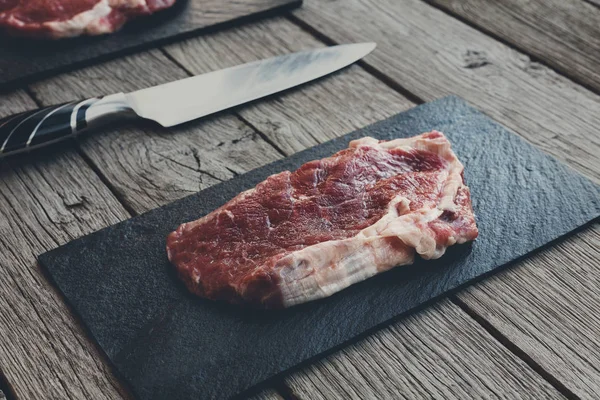Raw beef steak on dark wooden table background — Stock Photo, Image