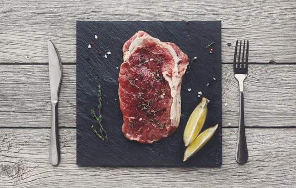 Steak de boeuf cru sur fond de table en bois foncé, vue de dessus — Photo