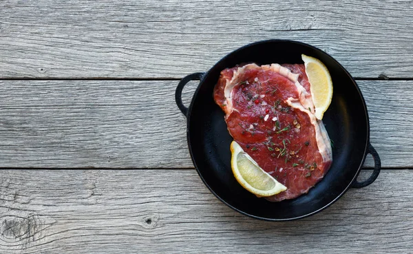 Steak de boeuf cru sur fond de table en bois foncé, vue de dessus — Photo