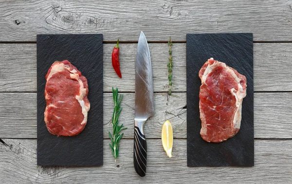 Raw beef steaks on dark wooden table background, top view — Stock Photo, Image