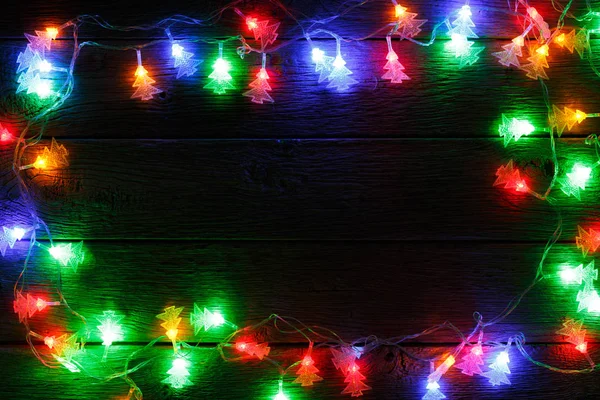 Christmas lights border on black wood background — Stock Photo, Image