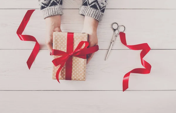 Womans hands give christmas gift in present box