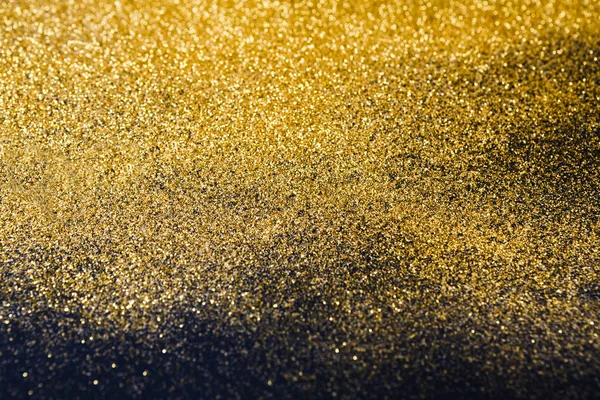 Textura de areia glitter dourada sobre fundo preto e abstrato . — Fotografia de Stock