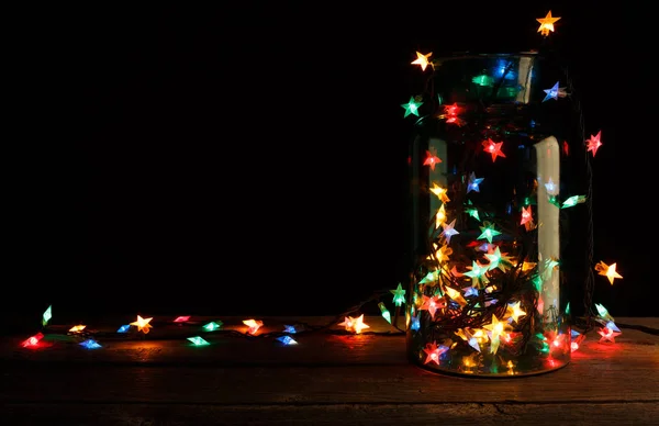 Christmas lights in glass jar on wood, holiday background — Stock Photo, Image
