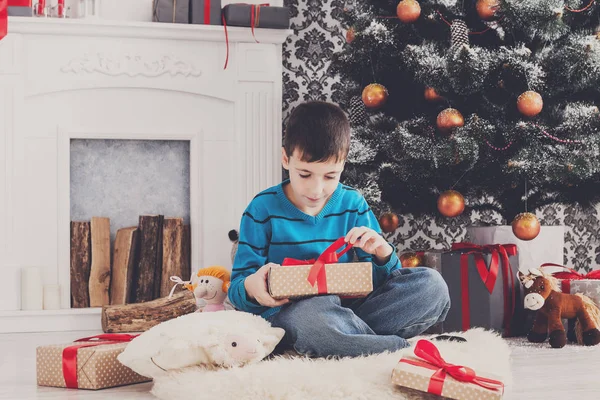 Süßer Junge mit Weihnachtsmütze beim Auspacken von Weihnachtsgeschenken — Stockfoto