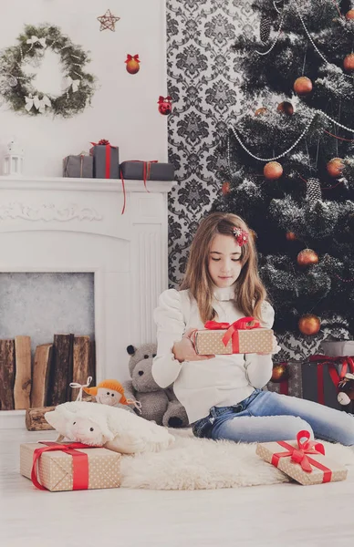 Bella ragazza in cappello di Babbo Natale scartando regali di Natale — Foto Stock