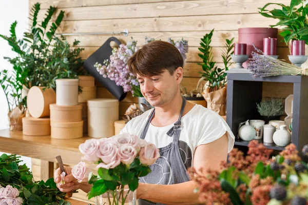 Homem assistente na entrega loja de flores fazer buquê de rosa — Fotografia de Stock