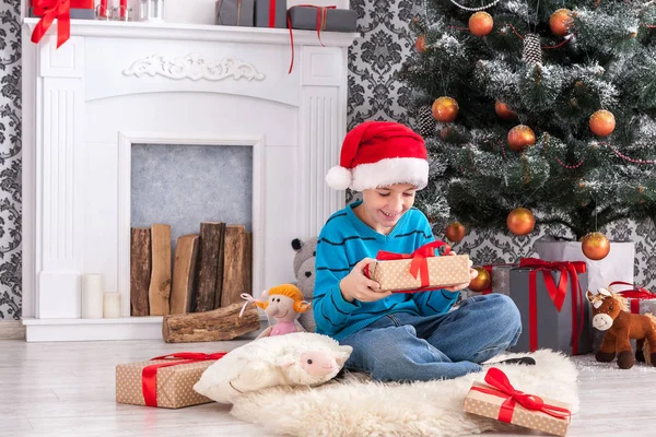 Süßer Junge mit Weihnachtsmütze beim Auspacken von Weihnachtsgeschenken — Stockfoto